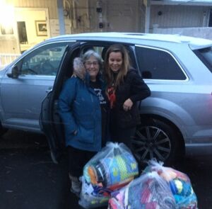 Two women stand together outside Matthew House with bags full of blankets for the homeless.